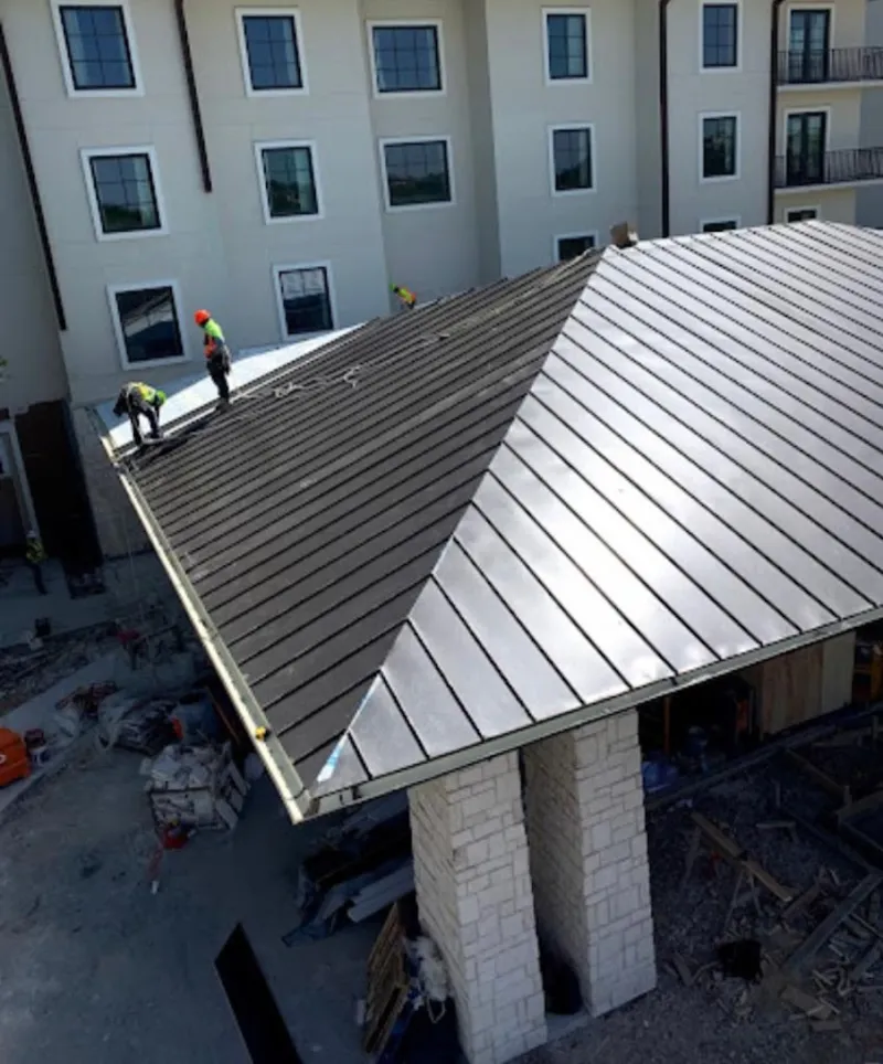 Crew installing standing seam metal roof panels on a commercial project in Rockaway